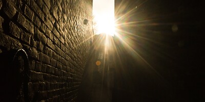 Gleißendes Licht strahlt von oben in eine Lücke zwischen zwei Gebäuden herein.