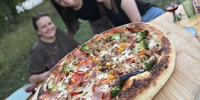 Pizza und drei Personen im Hintergrund
